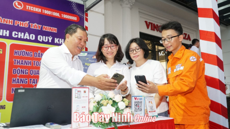 Nhân viên Điện lực thành phố Tây Ninh hướng dẫn người dân thanh toán hoá đơn tiền điện trực tuyến. Ảnh: Tâm Giang