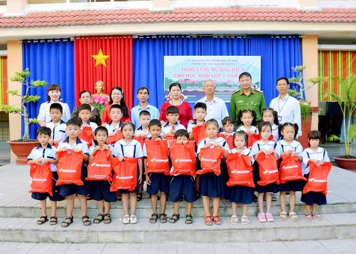 Ảnh: Lãnh đạo địa phương, Ban giám hiệu Trường TH Nguyễn Khuyến trao nón bảo hiểm cho học sinh